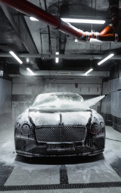 Luxury car being sprayed in a wash bay.